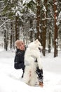 A human and a dog are best friends. Man and dog walk in snowy forest in winter in deep snow on a sunny day. Royalty Free Stock Photo