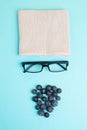 Human face made with a wool hat, glasses and blueberries as a beard, funny minimalist portrait, eco freak lifestyle, vegan