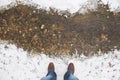 Human feet male wearing winter boots and jeans standing on bank of little spring creek covered with white fresh clean snow with