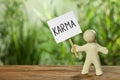 Human figure holding sign with word Karma on wooden table. Space for text