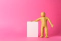 Human figure made of yellow plasticine holding blank sign on pink background. Space for text Royalty Free Stock Photo