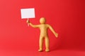 Human figure made of yellow plasticine holding blank sign on red background Royalty Free Stock Photo