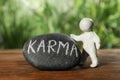 Human figure near stone with word Karma on wooden table, closeup Royalty Free Stock Photo