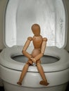 A human figure sitting on the toilet and holding his stomach, the concept of constipation, abdominal pain, poisoning and diarrhea, Royalty Free Stock Photo