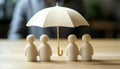 Human figures under umbrella on light wooden table. Insurance concept Royalty Free Stock Photo