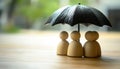 Human figures under umbrella on light wooden table. Insurance concept Royalty Free Stock Photo