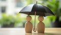 Human figures under umbrella on light wooden table. Insurance concept Royalty Free Stock Photo