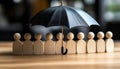 Human figures under umbrella on light wooden table. Insurance concept Royalty Free Stock Photo