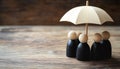 Human figures under umbrella on light wooden table. Insurance concept Royalty Free Stock Photo