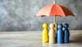 Human figures under umbrella on light wooden table. Insurance concept Royalty Free Stock Photo