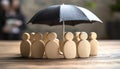 Human figures under umbrella on light wooden table. Insurance concept Royalty Free Stock Photo