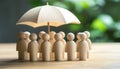 Human figures under umbrella on light wooden table. Insurance concept Royalty Free Stock Photo