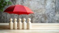 Human figures under umbrella on light wooden table. Insurance concept Royalty Free Stock Photo