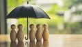 Human figures under umbrella on light wooden table. Insurance concept Royalty Free Stock Photo