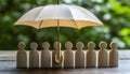 Human figures under umbrella on light wooden table. Insurance concept Royalty Free Stock Photo