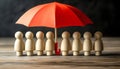 Human figures under umbrella on light wooden table. Insurance concept Royalty Free Stock Photo
