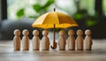 Human figures under umbrella on light wooden table. Insurance concept Royalty Free Stock Photo