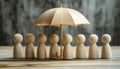 Human figures under umbrella on light wooden table. Insurance concept Royalty Free Stock Photo