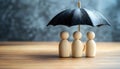 Human figures under umbrella on light wooden table. Insurance concept Royalty Free Stock Photo