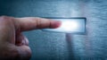 Human finger activating illuminated modern touch-sensitive button on sleek metallic surface in dark environment for futuristic Royalty Free Stock Photo