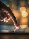 A human finger gently touching and interacting with a glowing touchscreen device against a backdrop of warm, blurred lights Royalty Free Stock Photo