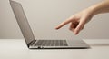 Human finger pointing at open silver laptop keyboard on white desk computer technology Royalty Free Stock Photo