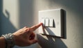 Human finger turns on the light switch. Hand presses button. White plastic switch on the wall. Indoor scene with light and Royalty Free Stock Photo