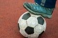 Human foot in a dirty sneaker on an old soccer ball Royalty Free Stock Photo