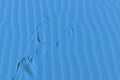 Human footprints on desert sand. Classic blue, color of the year 2020 Royalty Free Stock Photo