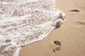 Human footprints on the sand with sea water. Foam from a wave on the sand. Royalty Free Stock Photo