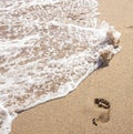 Human footprints on the sand with sea water. Foam from a wave on the sand. Royalty Free Stock Photo