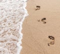 Human footprints on the sand with sea water. Foam from a wave on the sand with traces. Royalty Free Stock Photo