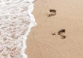 Human footprints on the sand with sea water. Foam from a wave on the sand with traces. Royalty Free Stock Photo