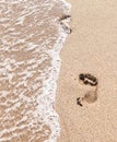 Human footprints on the sand with sea water. Foam from a wave on the sand with traces. Royalty Free Stock Photo