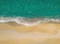 Human footprints on a sandy shore along the sea with breaking waves, aerial view directly above