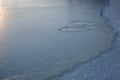 Human footprints visible beneath thin ice on frozen lake surface in cold winter Royalty Free Stock Photo