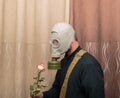 Men in gas mask standing in room and holding ros Royalty Free Stock Photo