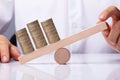 Human Hand Balancing Stacked Coins On Seesaw