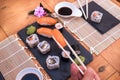 Human hand with chopsticks and a Nigiri sushi. Wooden table with sushi food