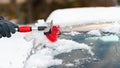 Human hand cleaning car from snow in wintertime day