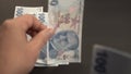 A human hand is counting 100 hundred Turkish Lira - TL money banknotes in a row and leave them