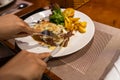 Human hand cutting delicious sirloin steak on white plate