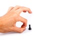 Human hand flicking a chess piece, huge hand flicks away a small tiny black pawn. Flick gesture isolated on white. Danger, anxiety