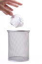 A human hand gently dropping crumpled paper ball into an empty metal trash can. Throwing away garbage, trashing an unused idea Royalty Free Stock Photo