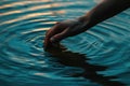 A human hand is gently extended towards something in the tranquil water, reaching out for an unseen object beneath the Royalty Free Stock Photo