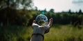 Human Hand Gently Holding Miniature Green Earth-like Planet, Trees and Grass, Serene Meadow Background Royalty Free Stock Photo