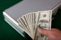 a hand is holding a metal briefcase filled with money and stacks of cash Royalty Free Stock Photo