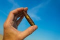 Human hand hold a bullet on a blue sky background