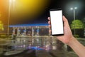 Human hand hold smartphone, tablet, cell phone with blank screen on blurry filling station background. Royalty Free Stock Photo