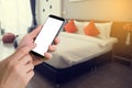 human hand hold smartphone, tablet, cell phone with blurry modern bedroom